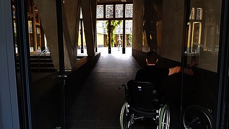 Iemand in een rolstoep bij de ingang van het stadhuis